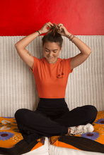 Charger l'image dans la galerie, femme-assise-qui-rigole-et-sattache-les-cheveux-qui-porte-un-tshirt-ohmyfruits-orange-cerise