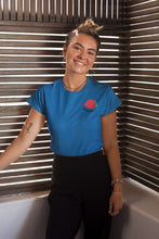 Charger l'image dans la galerie, mannequin-ravissante-femme-qui-sourit-et-qui-porte-un-tshirt-fraise-bleu-ohmyfruits-dans-une-piece-en-bois
