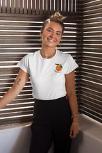 Charger l'image dans la galerie, mannequin-ravissante-femme-qui-sourit-et-qui-porte-un-tshirt-mandarine-blanc-ohmyfruits-dans-une-piece-en-bois