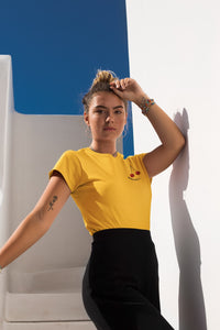 modele-sublime-femme-qui-porte-un-tshirt-jaune-cerise-ohmyfruits-et-quipose-dans-un-escalier-blanc-avec-le-ciel-bleu