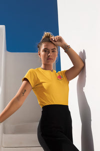 modele-sublime-femme-qui-porte-un-tshirt-jaune-fraise-ohmyfruits-et-quipose-dans-un-escalier-blanc-avec-le-ciel-bleu